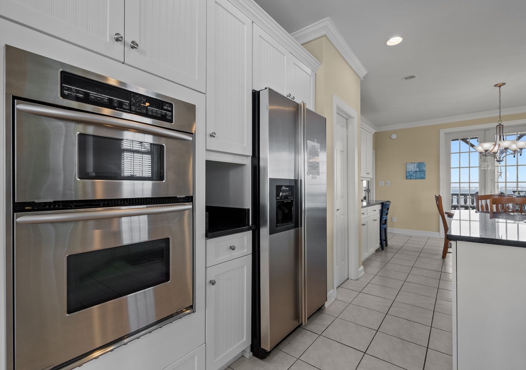 Your fully-equipped kitchen features stainless steel appliances, crisp white cabinetry, and seamless flow to the dining area for memorable meals.