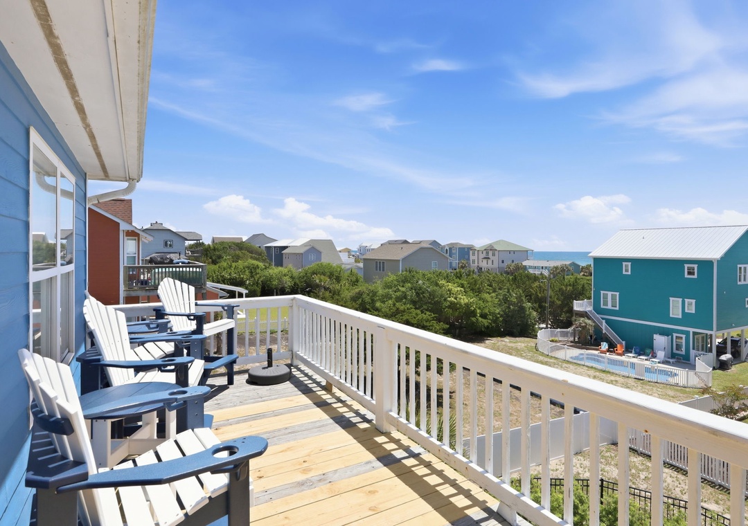 Coastal neighborhood with colorful beach houses, green dunes, and a glimpse of the ocean beyond—a serene setting for your beach getaway.