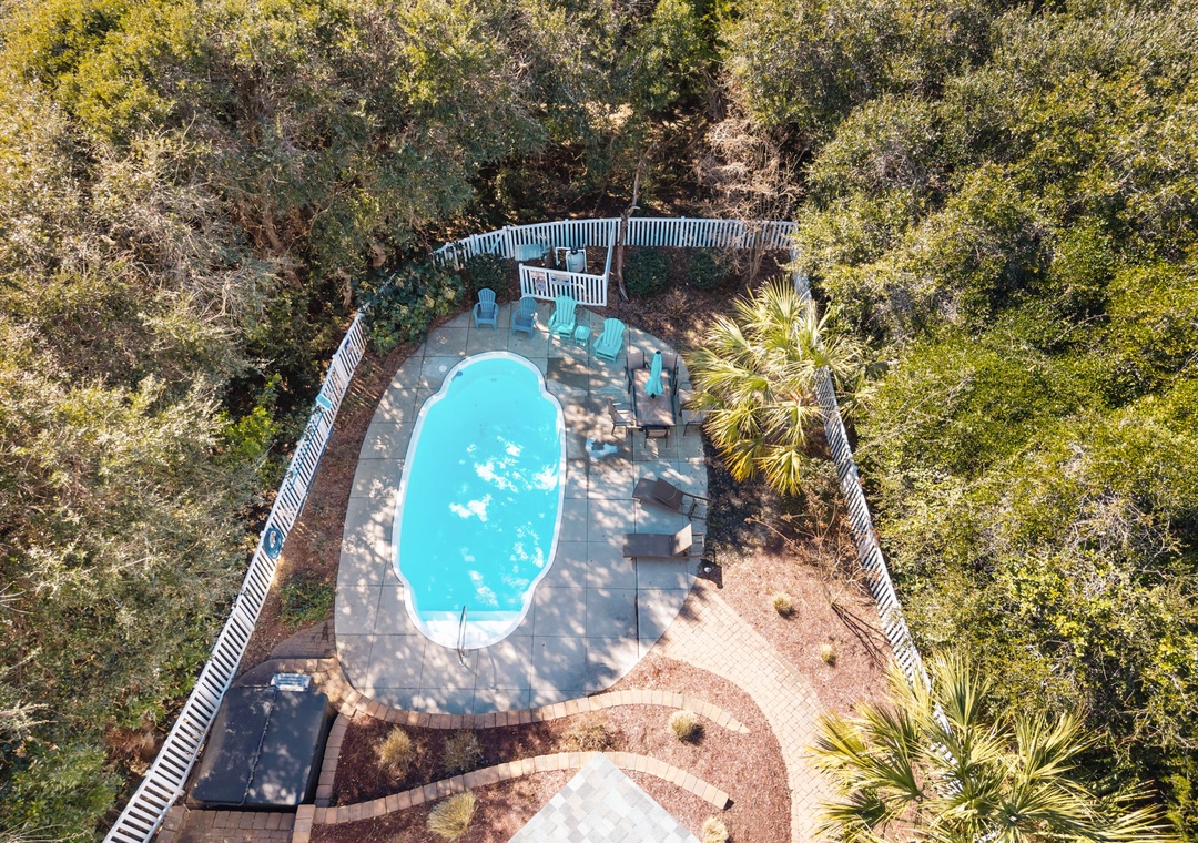 Aerial view of private pool area surrounded by lush vegetation and outdoor seating spaces.