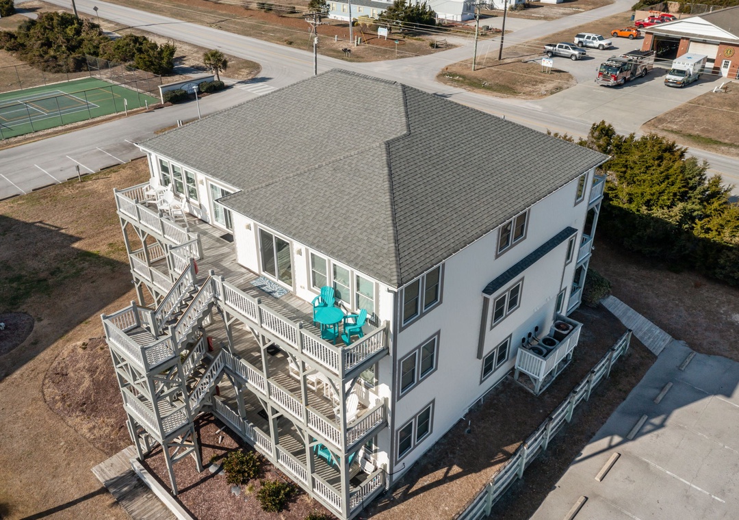 Multi-level beach house with expansive decks and outdoor dining, situated in a quiet coastal neighborhood near recreational facilities.
