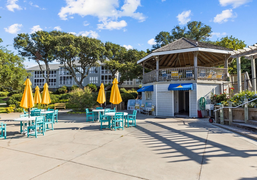Vibrant poolside dining area with sunny yellow umbrellas and turquoise tables creates the perfect spot for your morning coffee or afternoon refreshments.