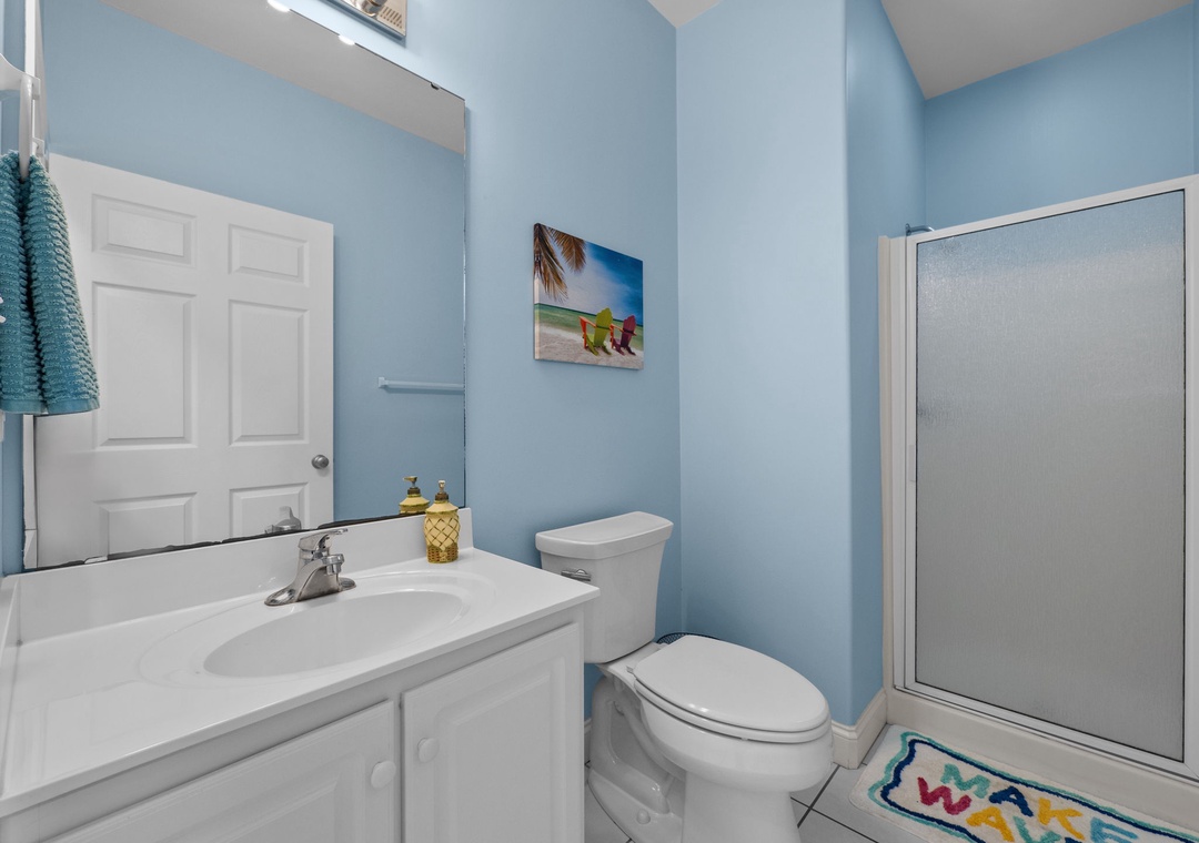 Refresh in your bright coastal bathroom with cheerful blue walls, beach artwork, and tropical touches that make every morning feel like vacation.