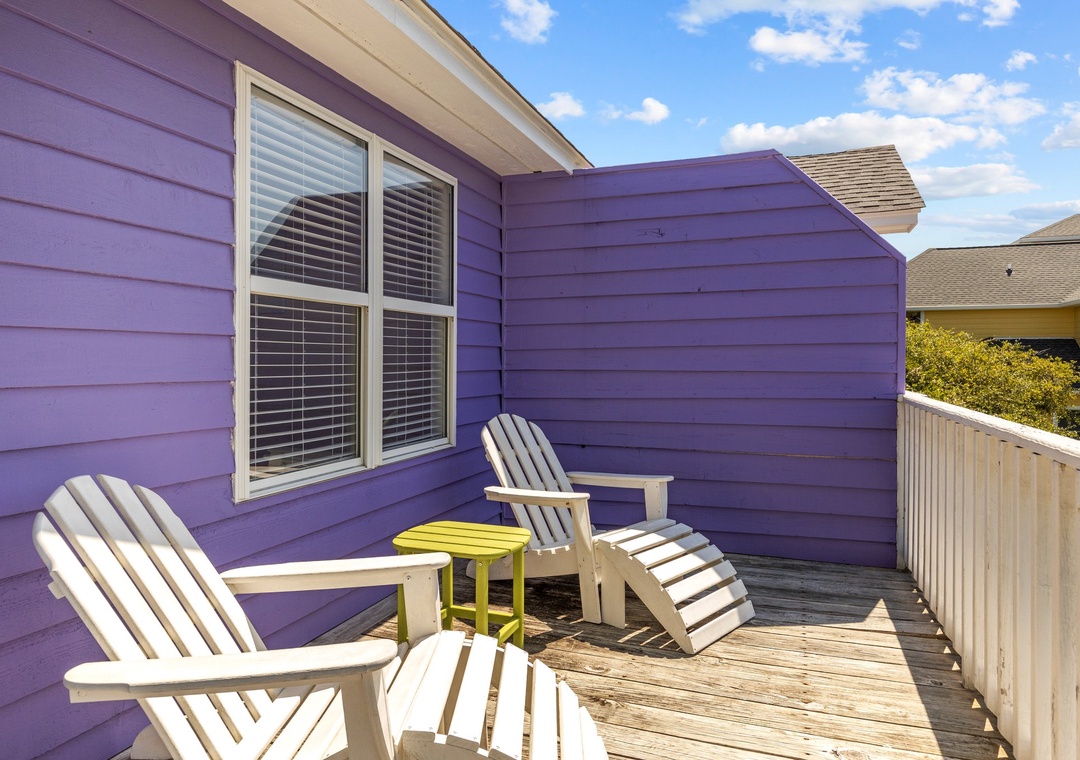 Relax on your private deck with classic Adirondack chairs, soaking up sunshine against vibrant purple siding—your perfect outdoor retreat awaits.