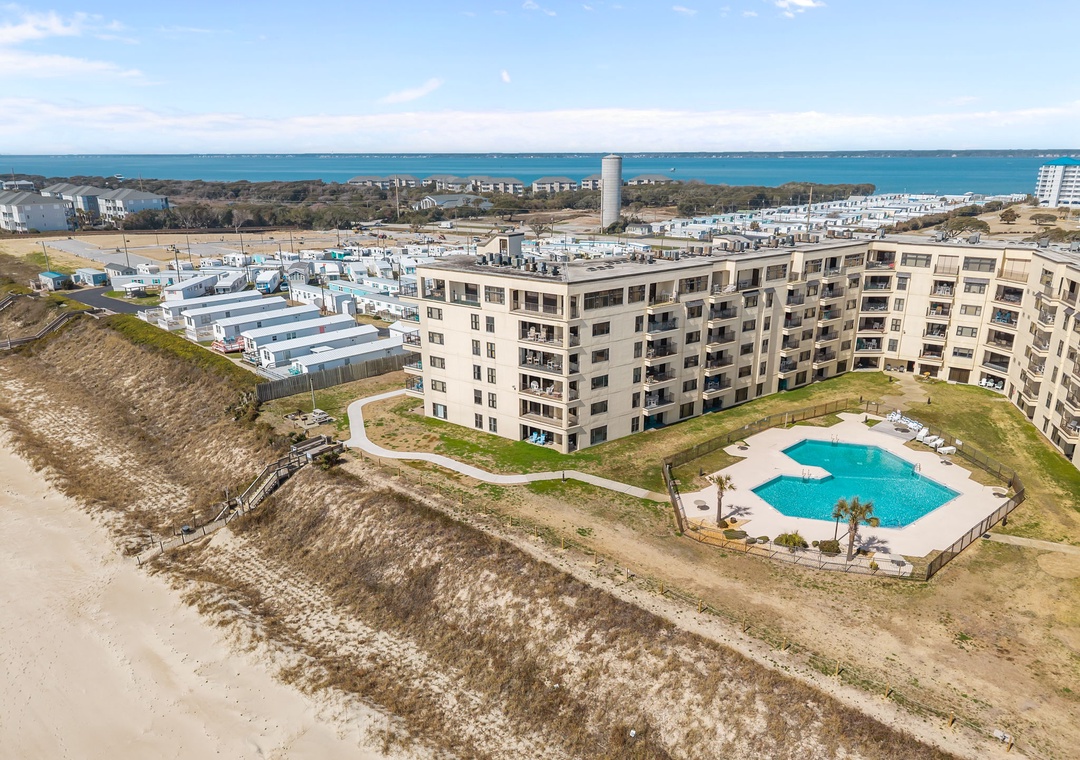 Beachfront resort property with ocean access and a sparkling pool, set along the coast with views of the bay and surrounding area.