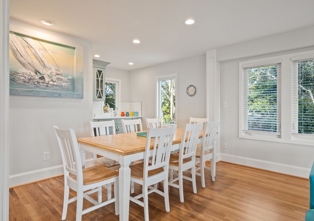 Gather your group around this bright dining table where natural light streams through generous windows, creating the perfect space for memorable meals together.