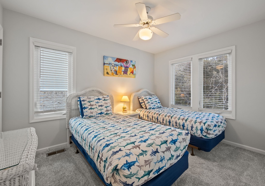 Your bright twin bedroom features playful shark-themed bedding and wicker furniture, creating the perfect coastal hideaway for kids or friends.