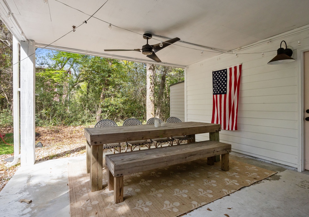 Gather around your private covered patio with rustic dining table and benches, perfect for morning coffee or evening meals under twinkling lights.