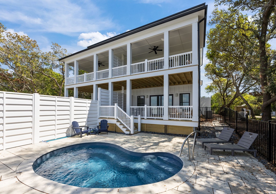 A charming two-story rental home with wraparound porches and private pool, nestled among mature trees in a peaceful residential setting.