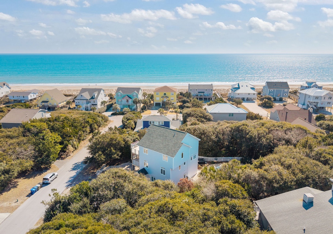 Charming coastal community with colorful beachfront homes nestled among native vegetation, just steps from pristine sandy shores.