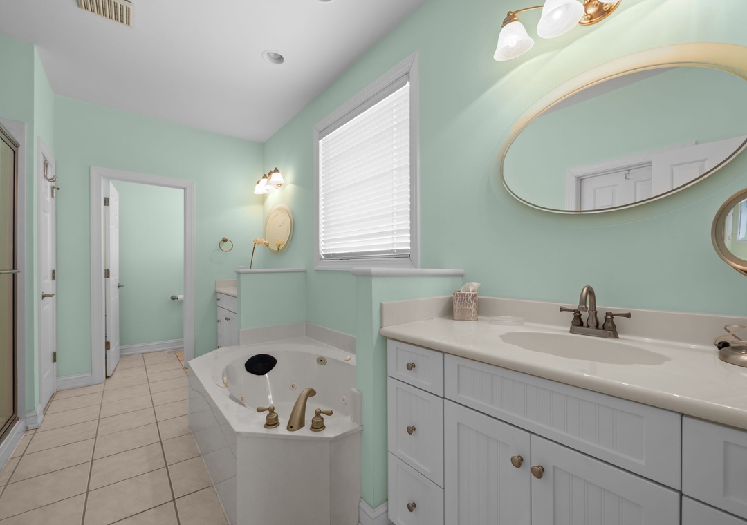 Relax in your spacious bathroom featuring soothing mint green walls, a luxurious soaking tub, and bright natural light streaming through the window.