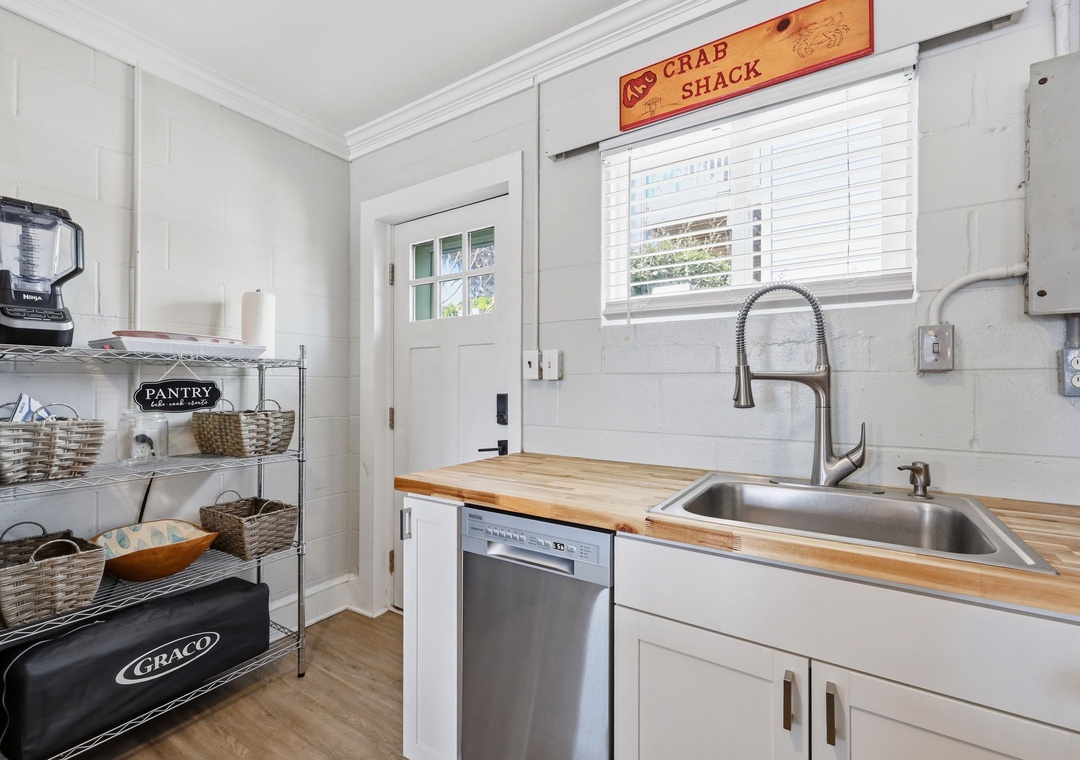 Your kitchen offers warm butcher block countertops, a farmhouse-style sink, and all the essentials for preparing meals in coastal comfort beneath playful 
