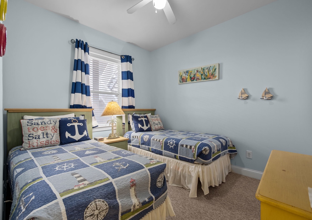 Your cozy nautical-themed bedroom features twin beds with charming ocean decor, perfect for kids or friends sharing seaside dreams.