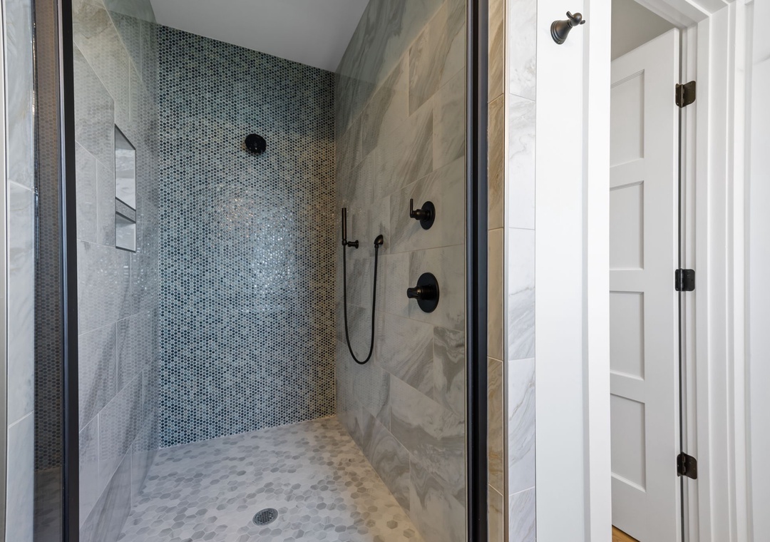 Step into your luxurious walk-in shower with stunning mosaic tile accent wall and rainfall showerhead for a spa-like experience.