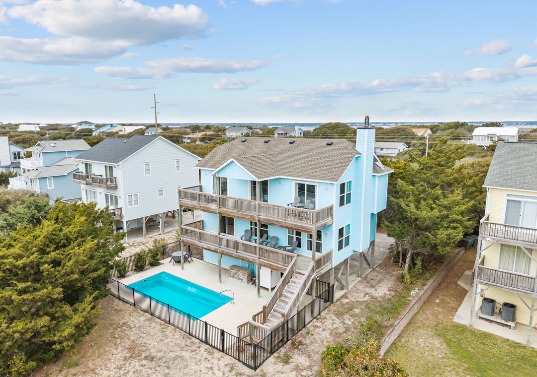 Aerial view of beachfront vacation homes nestled among coastal vegetation, with swimming pools and easy beach access in this scenic waterfront community.