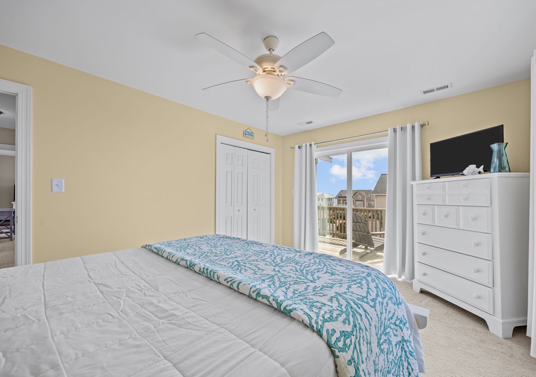 Unwind in your bright bedroom with ocean-themed bedding, ceiling fan, and TV for cozy evenings.