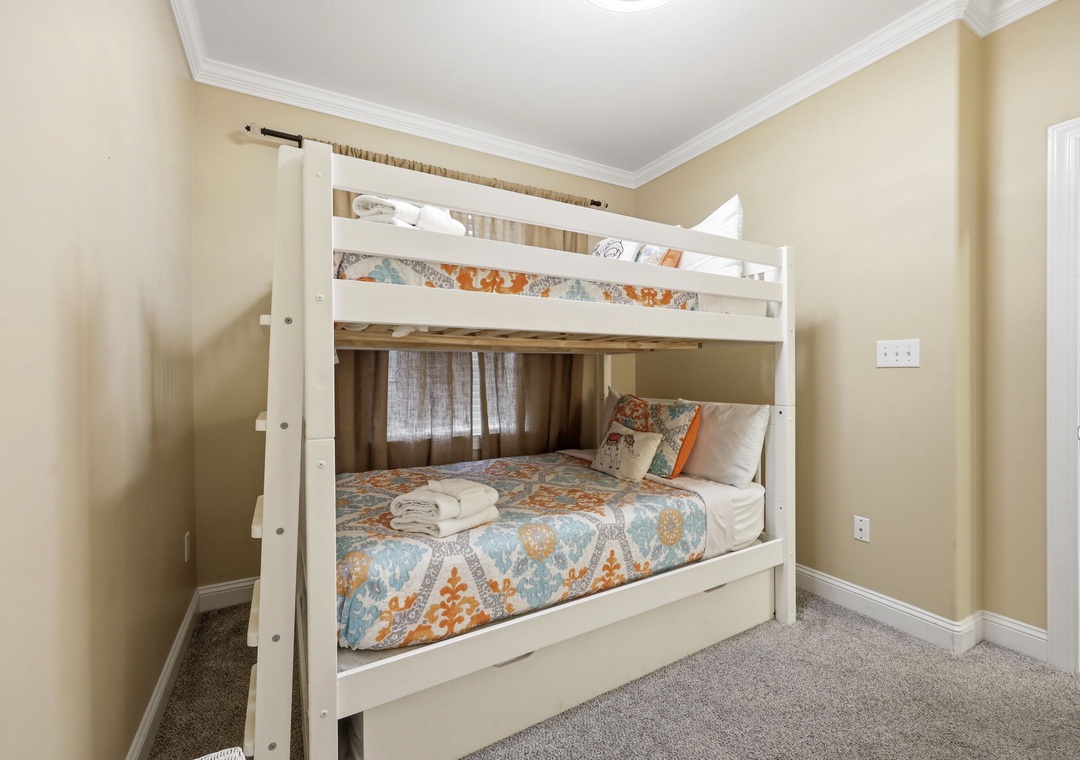 Cozy bunk room with a sturdy white frame, colorful patterned bedding, and fresh towels ready for your group or family to settle in comfortably.