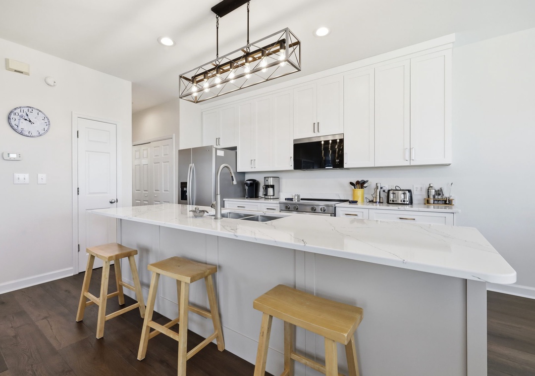 Your bright, modern kitchen features gleaming quartz countertops, stainless steel appliances, and a spacious island perfect for morning coffee or preparing meals during your stay.