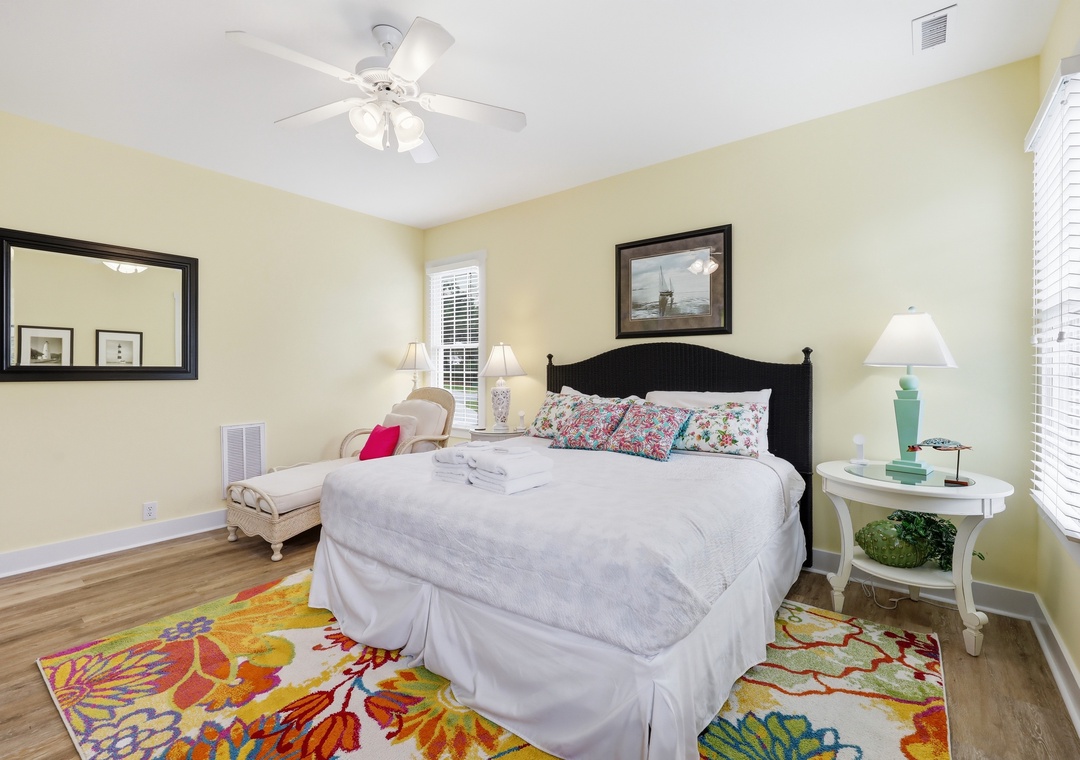 Settle into your bright coastal bedroom with plush linens, cheerful tropical accents, and gentle breezes from the ceiling fan above. A peaceful space to rest and recharge.