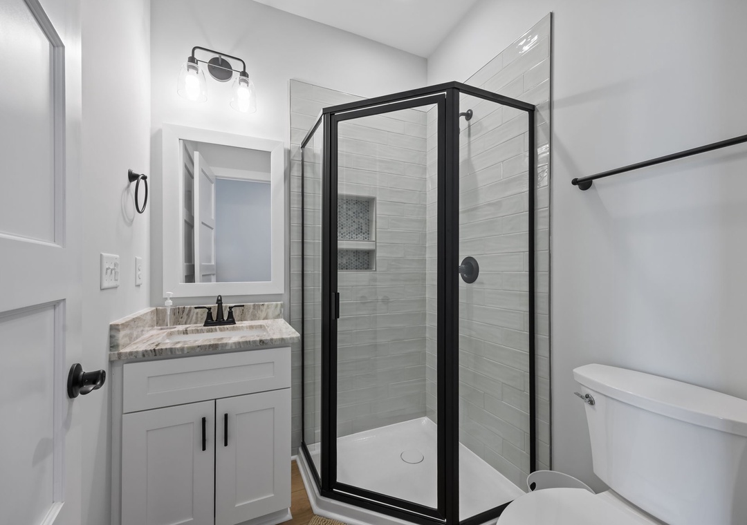 Step into your pristine bathroom featuring elegant marble countertops, a spacious glass shower with modern fixtures, and thoughtful design touches.