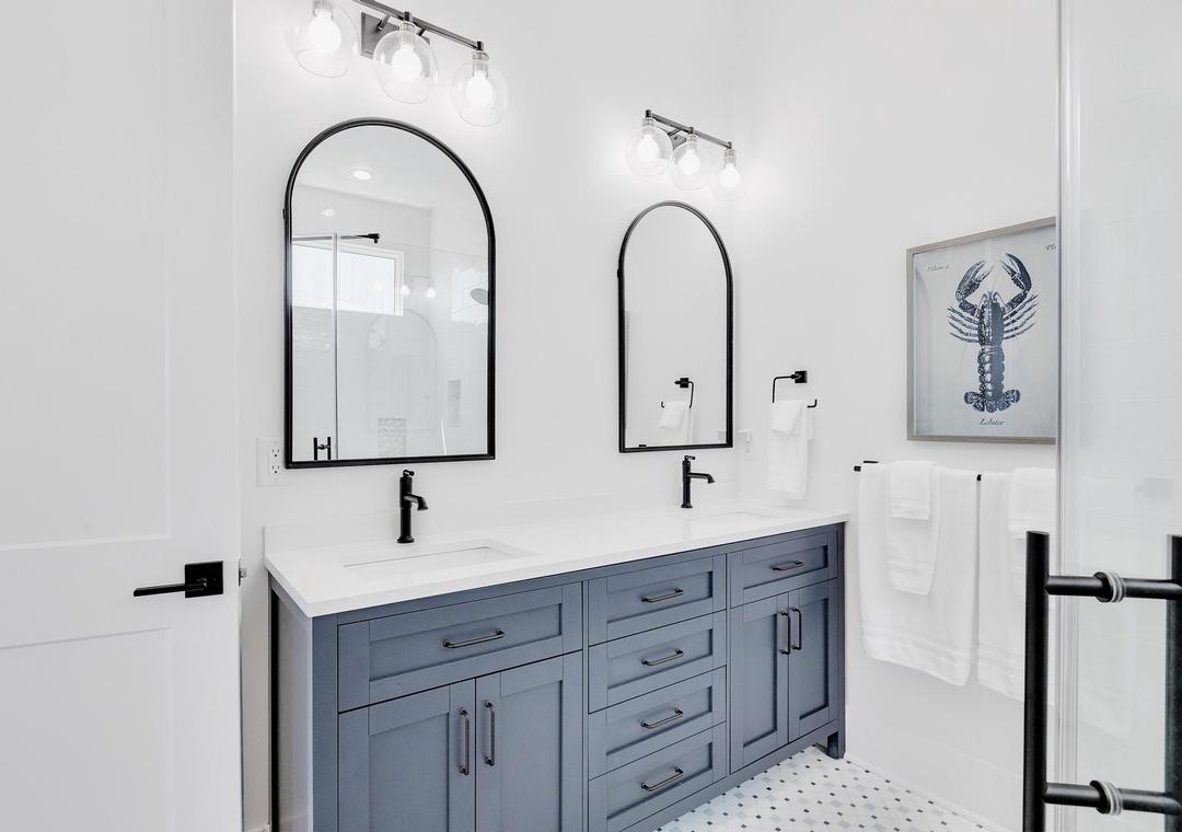 Freshen up in your bright, modern bathroom with double vanity, sleek black fixtures, and coastal-inspired artwork. Your clean white towels are already waiting for you.