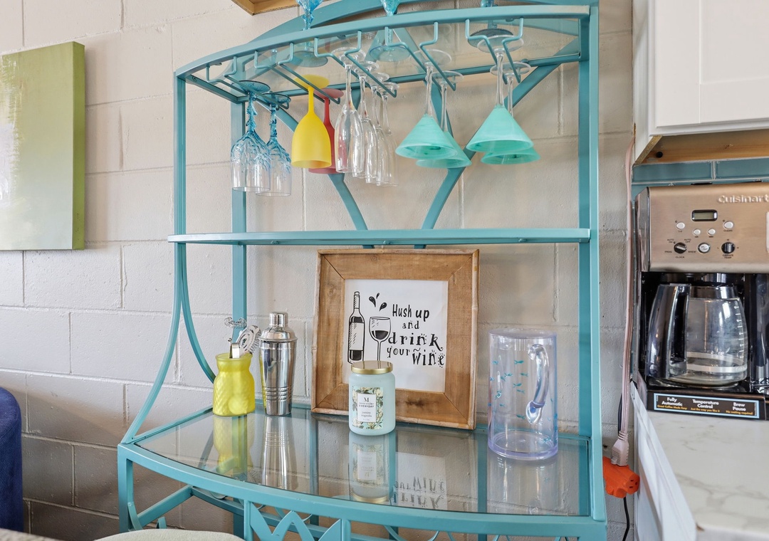 A charming turquoise bar cart awaits your evening cocktails, with glassware and wine accessories ready for you to unwind and sip in style.