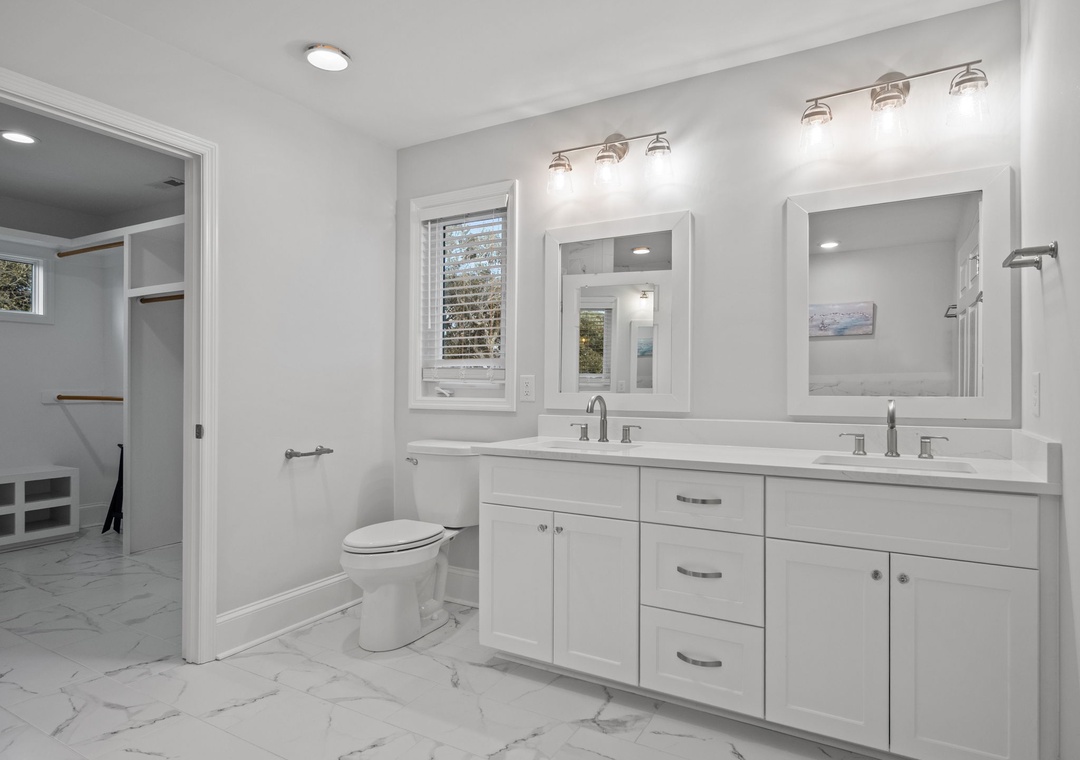 Indulge in your private spa-like bathroom with dual vanities, elegant marble floors, and a spacious walk-in shower for the ultimate morning routine.