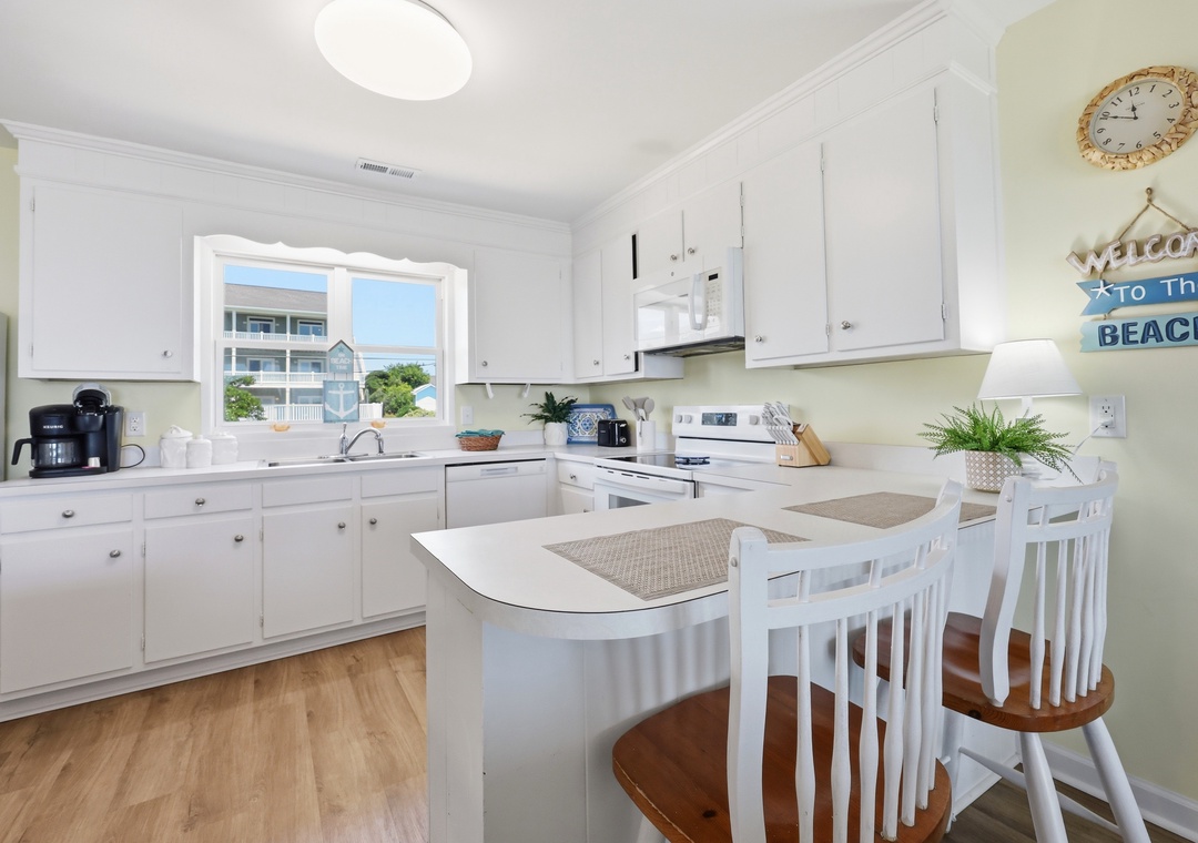 Picture yourself preparing meals in this bright, coastal-inspired kitchen with beach views inviting you to unwind. The open layout and cheerful décor create a welcoming space where your vacation memories begin.