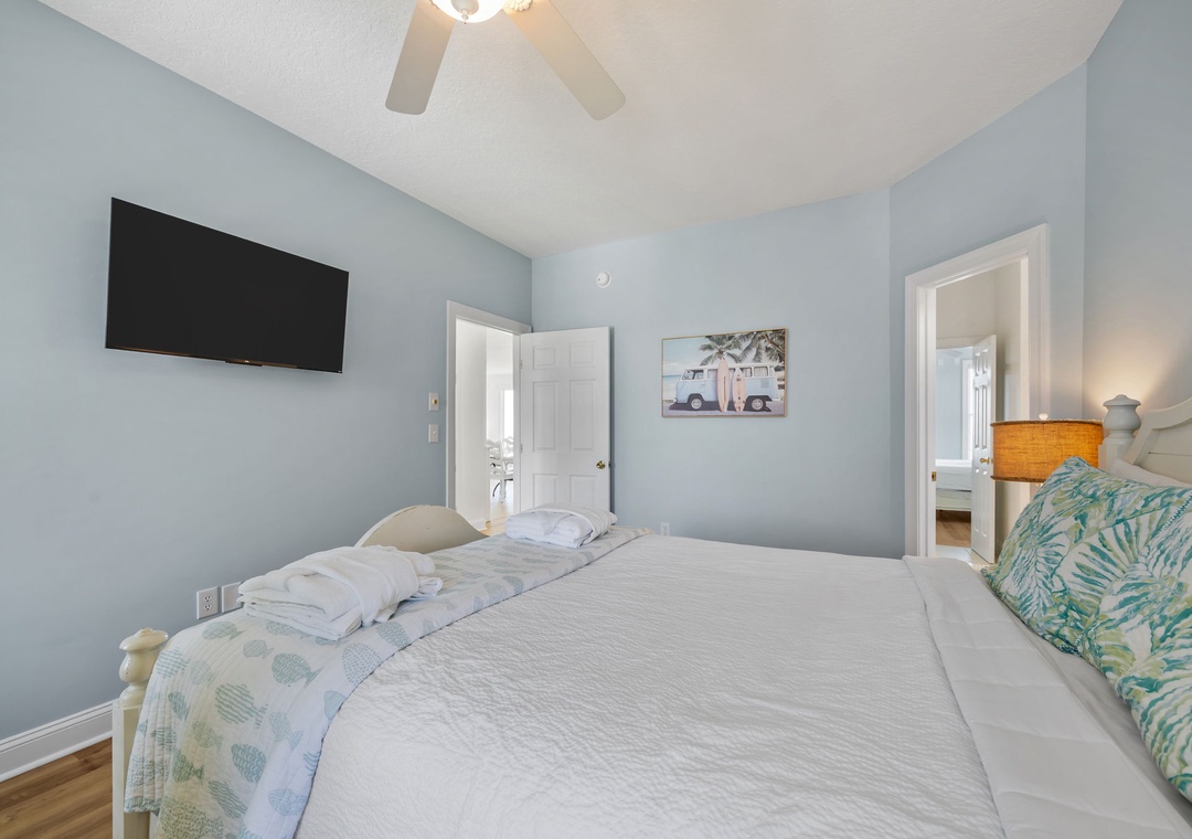 Drift off in this serene bedroom featuring soft blue walls, crisp linens, and tropical touches that create your perfect coastal retreat.