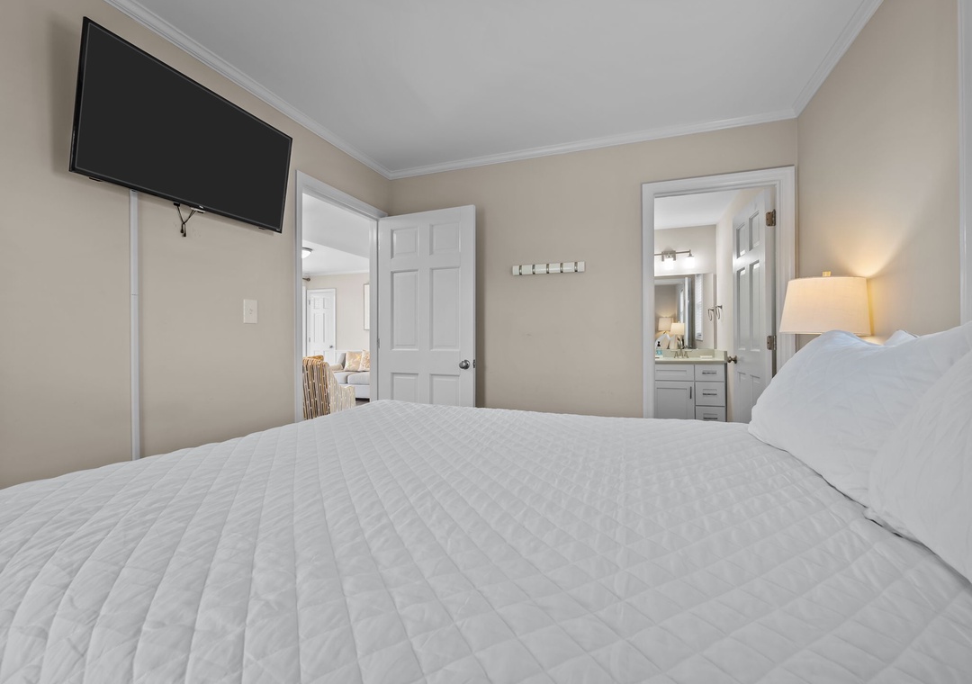 Sink into crisp white linens in your serene bedroom, where warm lighting and your private en-suite await.