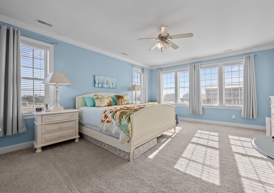 Wake up in this serene coastal bedroom where soft blue walls and natural light create your peaceful retreat.