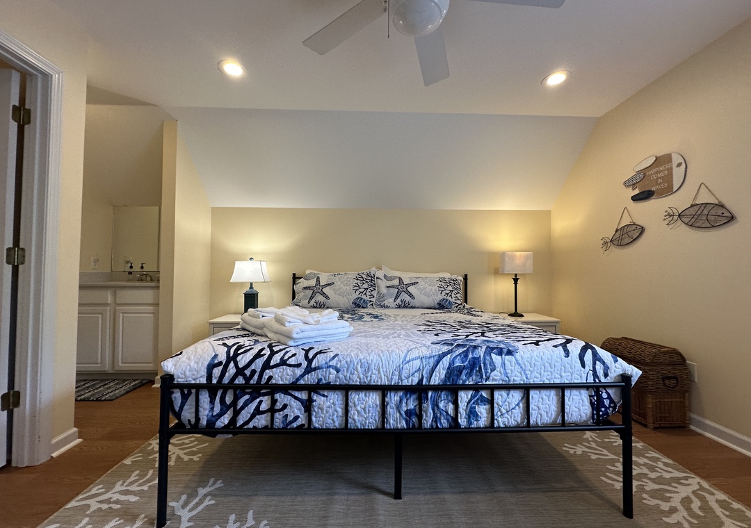 Unwind in your coastal-inspired bedroom with a plush queen bed, ceiling fan, and beachy décor. The en-suite bathroom and soft lighting create a restful retreat.