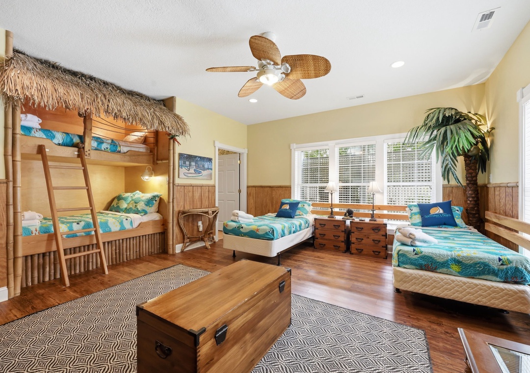 Gather the family in this tropical-themed bedroom featuring a unique bunk bed with thatched canopy and multiple comfy beds—perfect for creating vacation memories together.