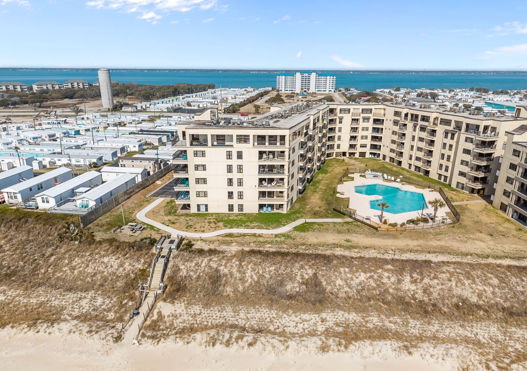 Coastal property complex featuring modern apartments with swimming pool, just steps from pristine beachfront access.