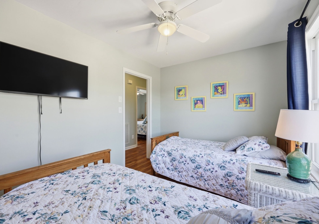 Relax in your cozy bedroom with comfortable beds, cheerful artwork, and modern conveniences like a flat-screen TV and ceiling fan to keep you comfortable during your stay.