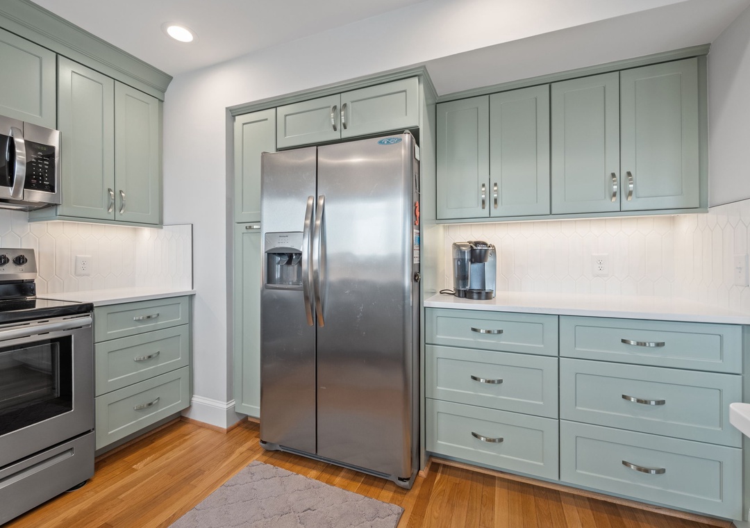 Your fully equipped kitchen features sage green cabinets, stainless steel appliances, and ample counter space for preparing memorable meals.