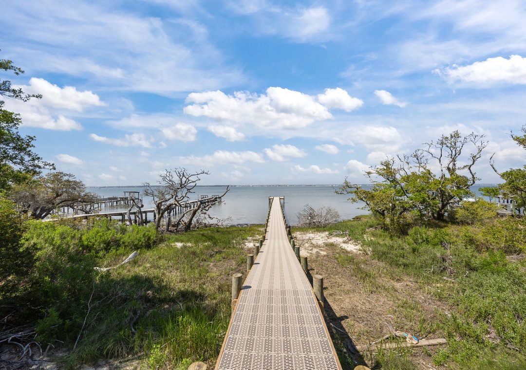 Waterfront location with wooden boardwalk leading to natural coastline, surrounded by native vegetation and peaceful bay views.