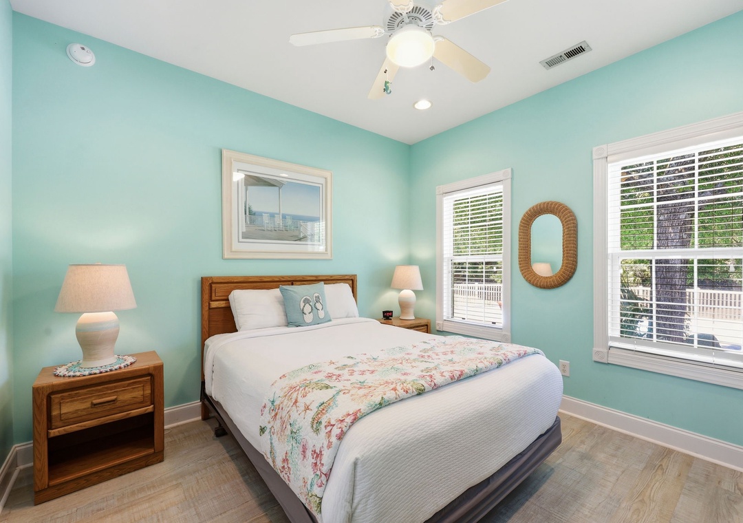 Drift off in your serene coastal bedroom, where soft turquoise walls and warm wood tones create a soothing escape. Natural light pours through plantation shutters framing your peaceful retreat.