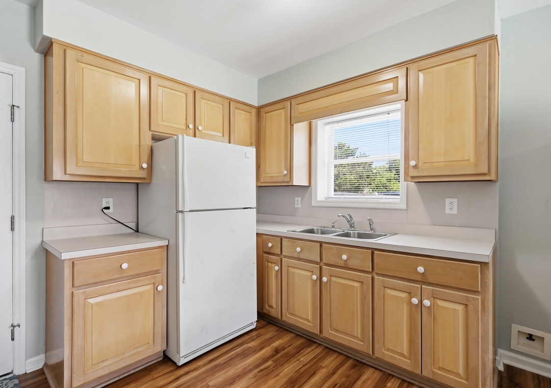 Step into your well-equipped kitchen, where warm wood cabinetry and bright natural light create a welcoming space for preparing meals and gathering with loved ones during your stay.