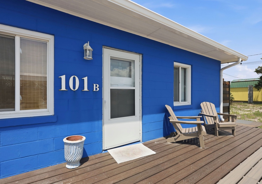 Unit 101B features a welcoming entrance with a spacious deck perfect for morning coffee or evening relaxation, marked by clear numbering and charming coastal touches.