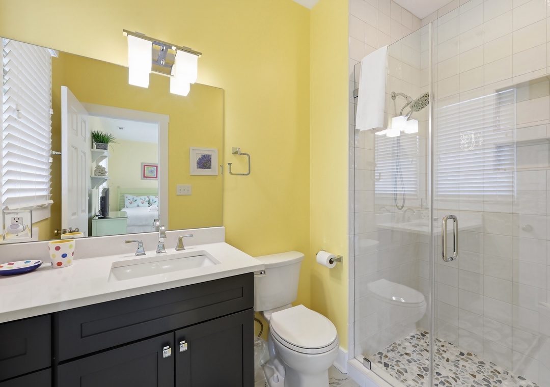 Brighten your mornings in this cheerful bathroom with a spacious walk-in shower, modern vanity, and playful pops of color. Fresh towels and plenty of light await your arrival.