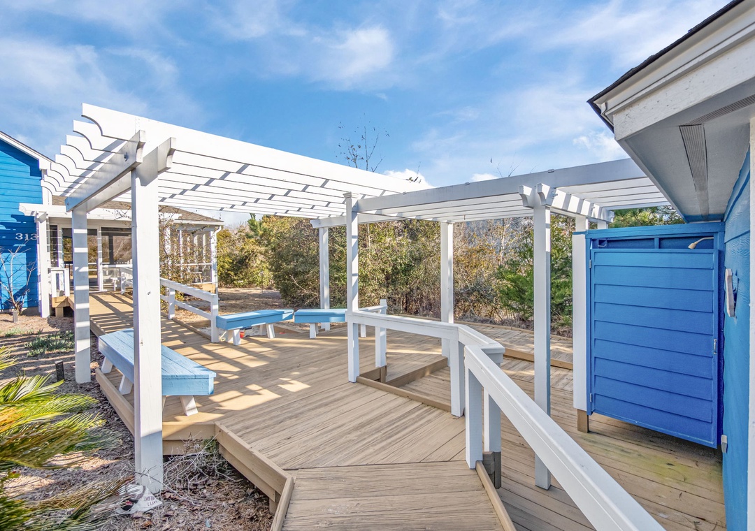 Relax on your private deck with pergola shade and outdoor dining space, surrounded by coastal charm.