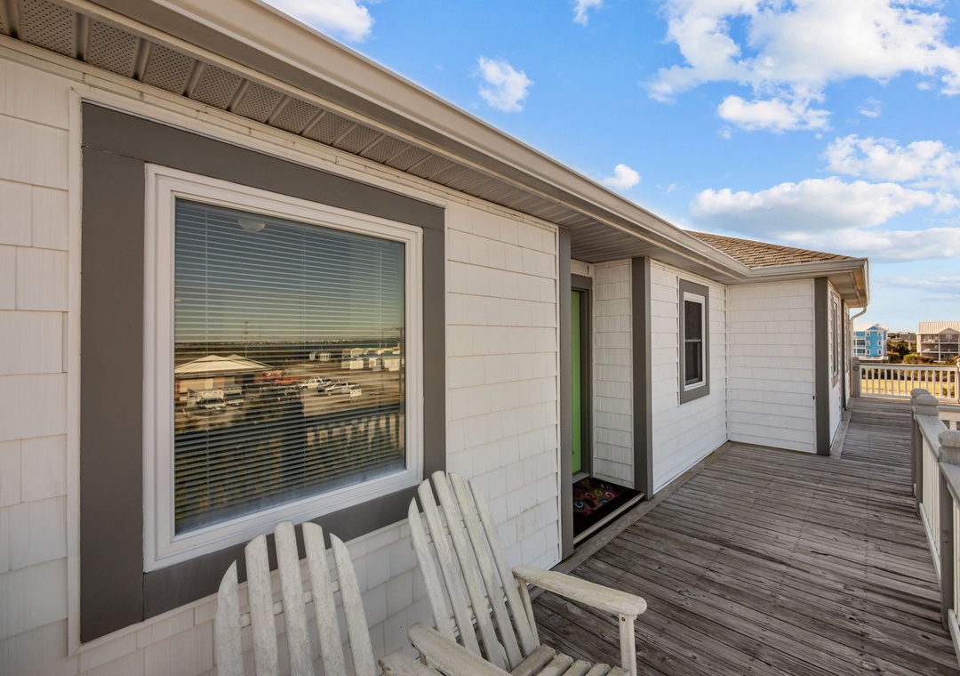 Modern beach house exterior features expansive deck with oceanfront views and contemporary coastal design.