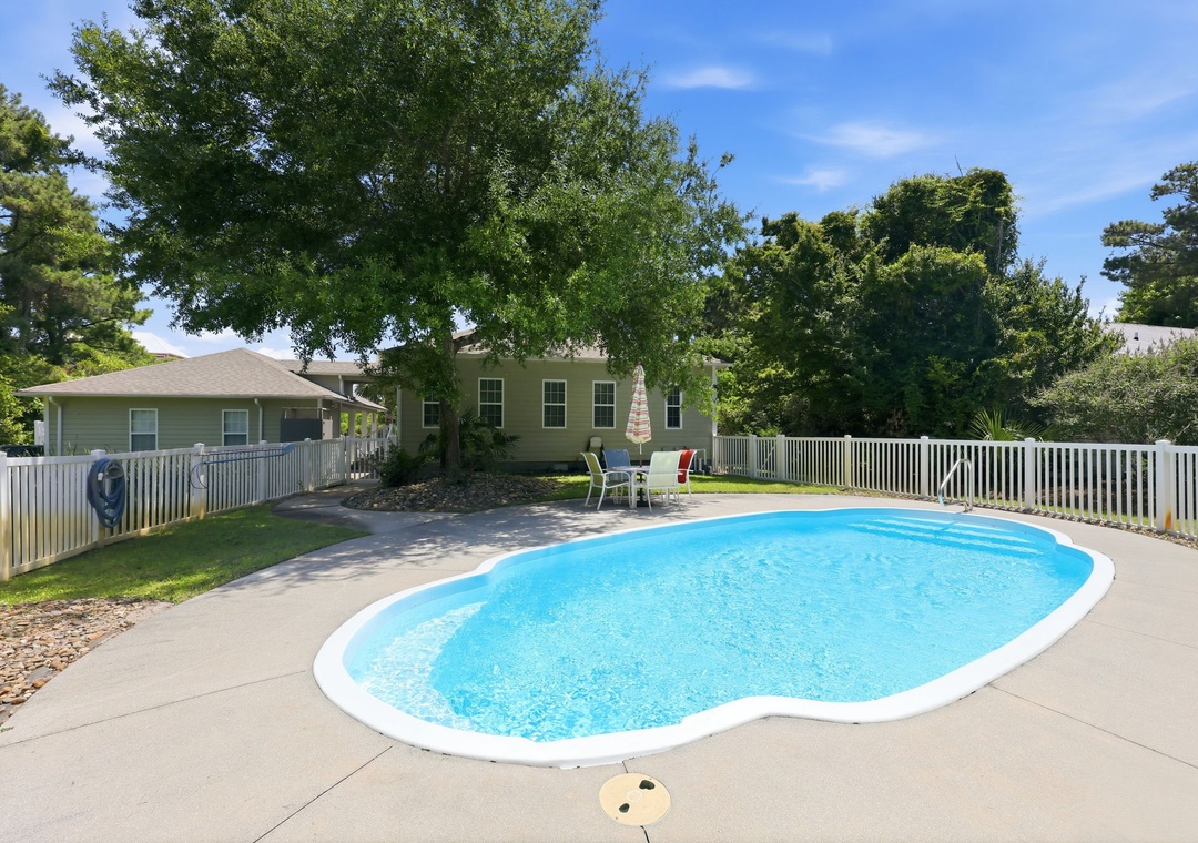 This inviting property features a private outdoor pool framed by a spacious, fenced-in backyard with mature trees and ample seating, creating a peaceful retreat for relaxing sunny days.