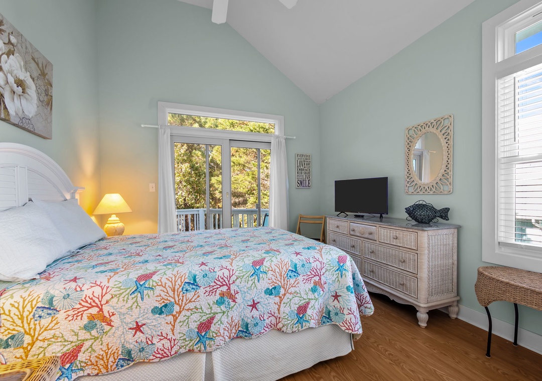 Sink into your coastal-themed bedroom with soft mint walls and cheerful coral bedding, complete with TV and private balcony access.