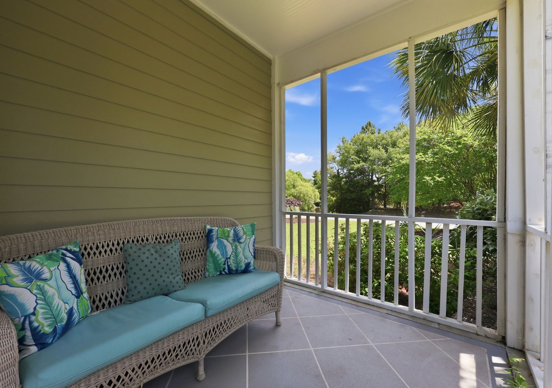 Relax on your private screened balcony with comfortable seating, where lush tropical greenery and brilliant blue skies create your peaceful retreat.