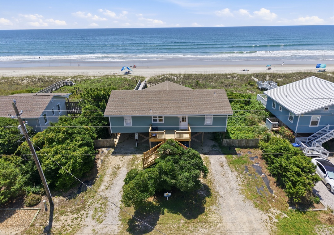 Aerial view showing a beachfront duplex property with direct access to pristine sandy shores and the Atlantic Ocean, surrounded by coastal vegetation and neighboring beach homes.