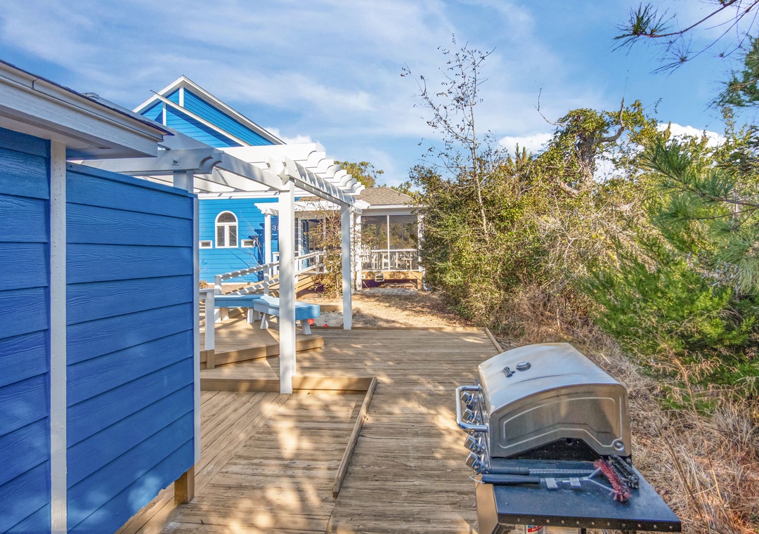 Charming blue cottage with spacious deck and outdoor pizza oven creates the perfect coastal retreat for memorable gatherings.
