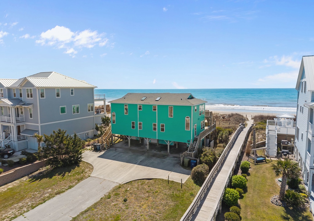Bright turquoise beachfront home with boardwalk access to pristine sandy shores and crystal-clear ocean waters.