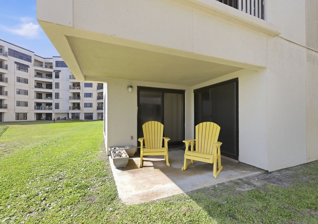 Unwind on your private covered patio with cheerful Adirondack chairs overlooking lush green lawns—perfect for morning coffee or evening relaxation in your peaceful retreat.