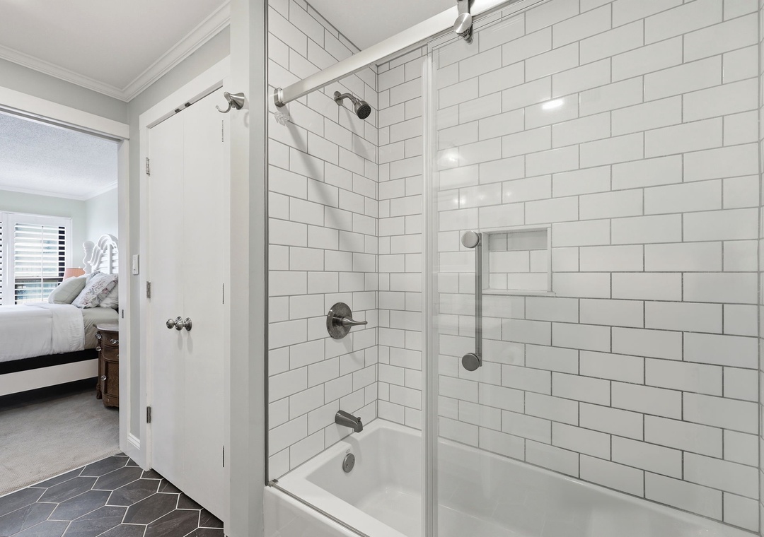 Step into your private ensuite, where crisp white subway tile and modern fixtures create a spa-like retreat. The spacious shower offers a refreshing escape after a day of exploring.